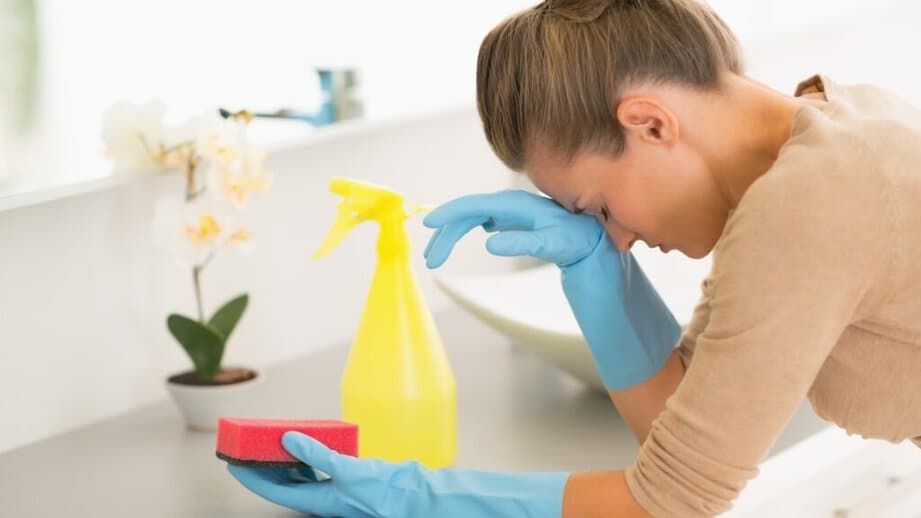 woman frusturated while cleaning with sponge in hand