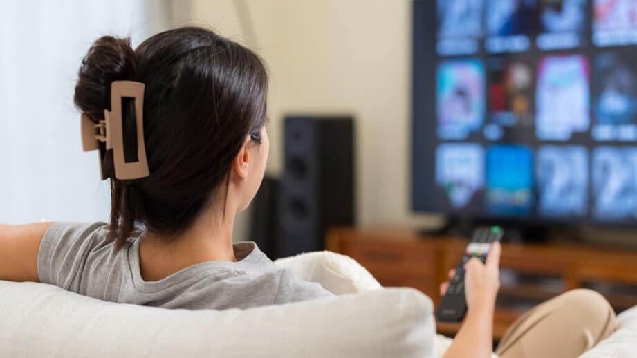 Woman sitting on couch watching tv