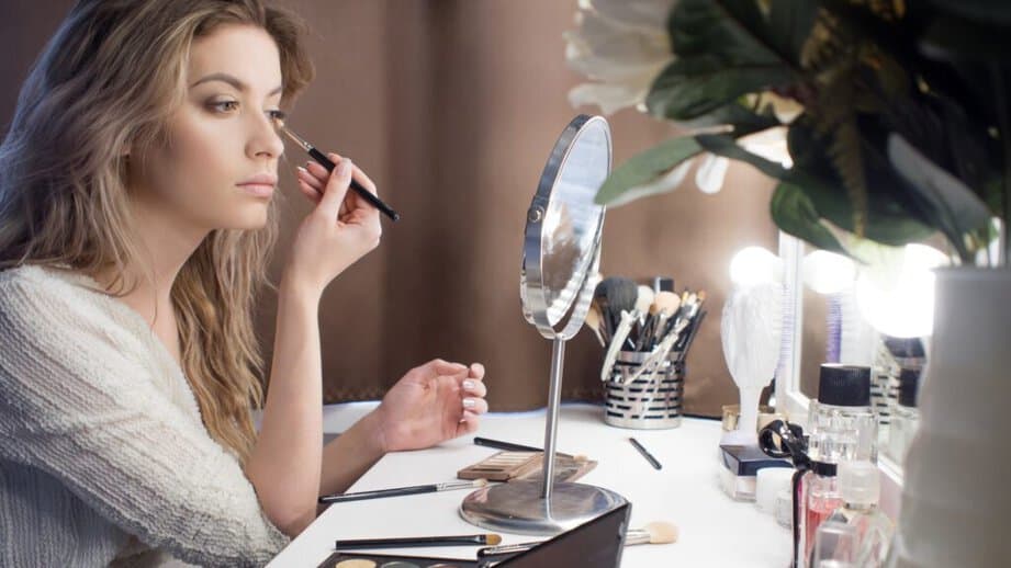 woman putting on her makeup in a mirror