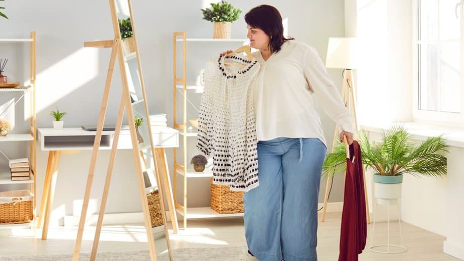 curvy woman looking in mirror to decide outfit