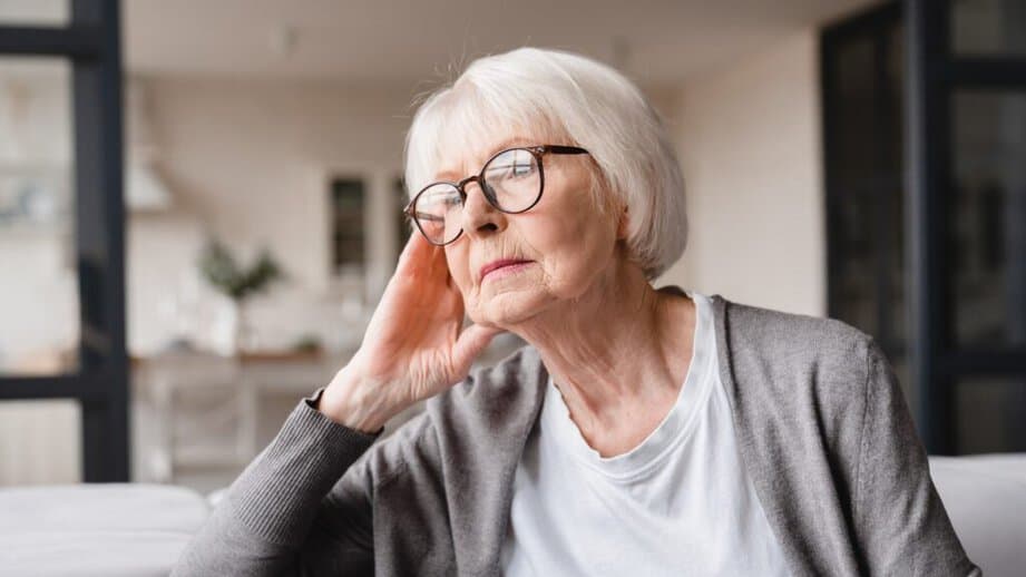 older woman with glasses looking sad