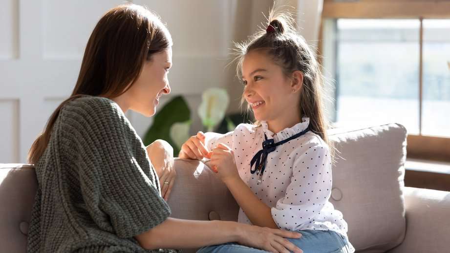 mother and daughter sitting on a couch talking