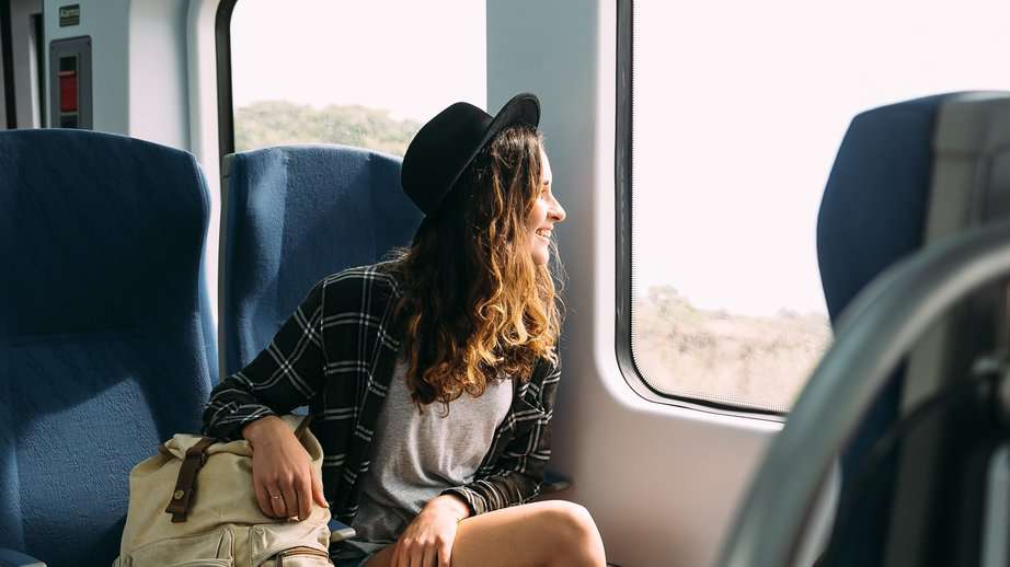 woman looking out train window while traveling