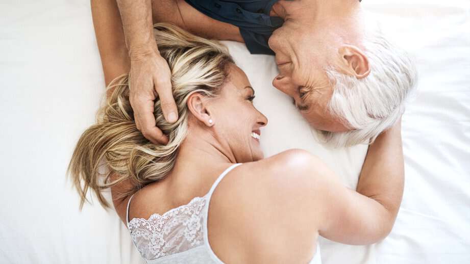 affectionate mature couple lying in bed in love