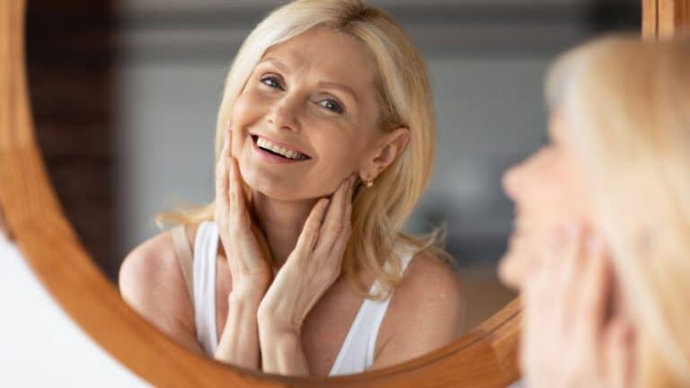 beautiful middle aged woman looking in mirror smiling