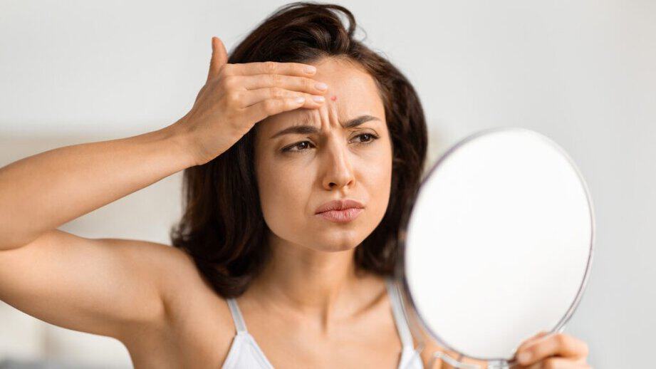 woman looking in mirror concerned about skin