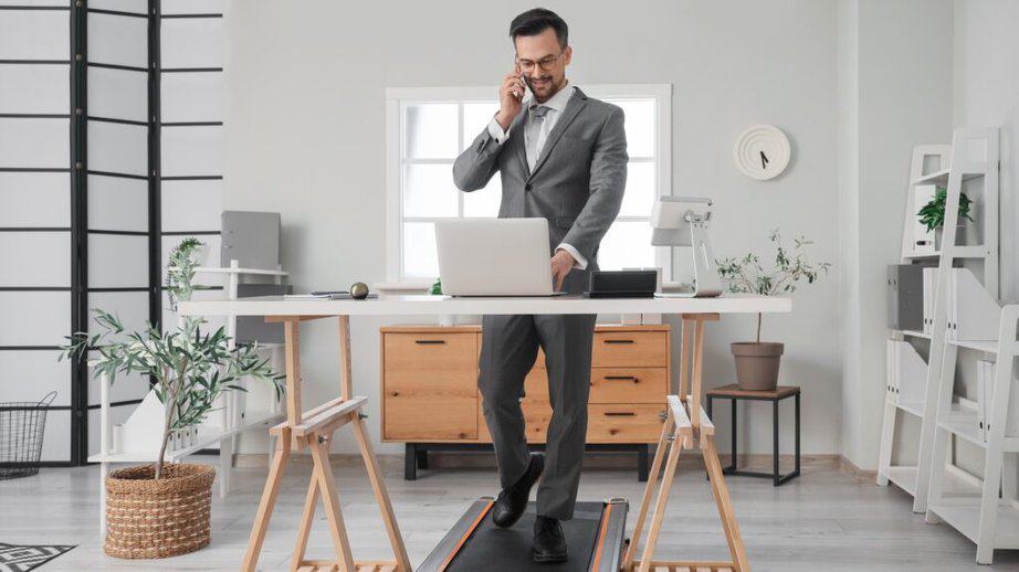 man at standing desk working and walking on tredmill