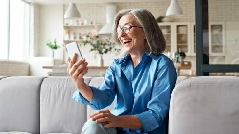 older woman looking at phone happily