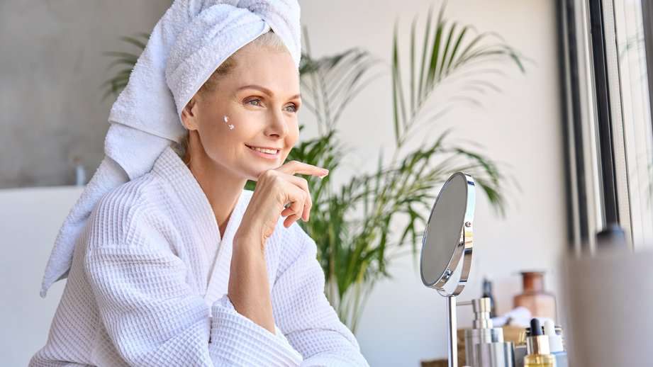 older woman looking in the mirror with robe on